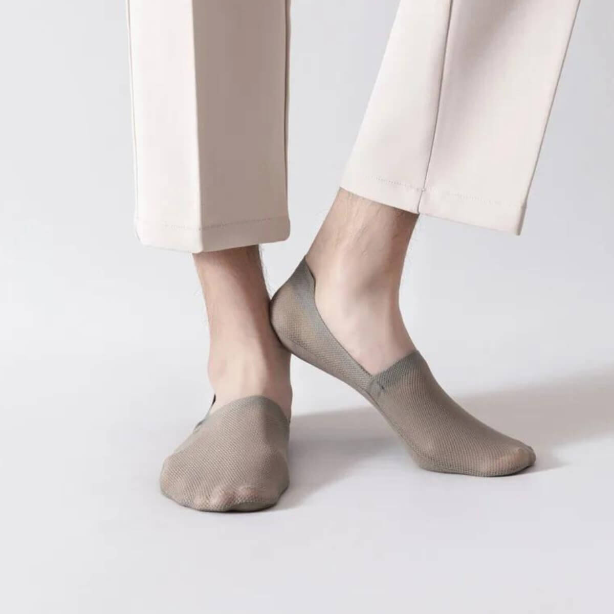 Beige Socken, dehnbar, an Füßen mit heller Hose getragen.